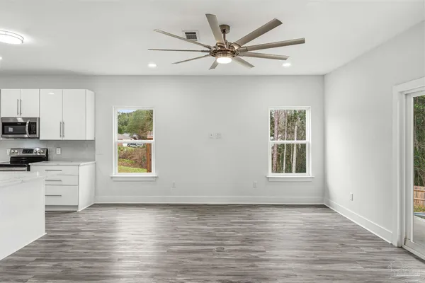 a view of an empty room with a window and wooden floor