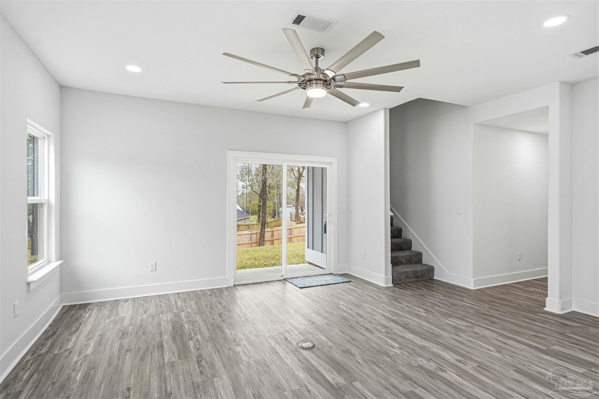 4446 Antioch Road Crestview, FL 32536 - Photo 7 of 43 an empty room with wooden floor fan and windows