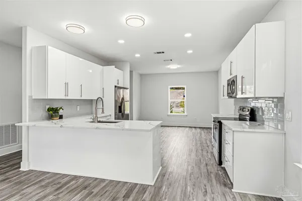 a large kitchen with stainless steel appliances granite countertop a stove a sink dishwasher and a refrigerator with wooden floor