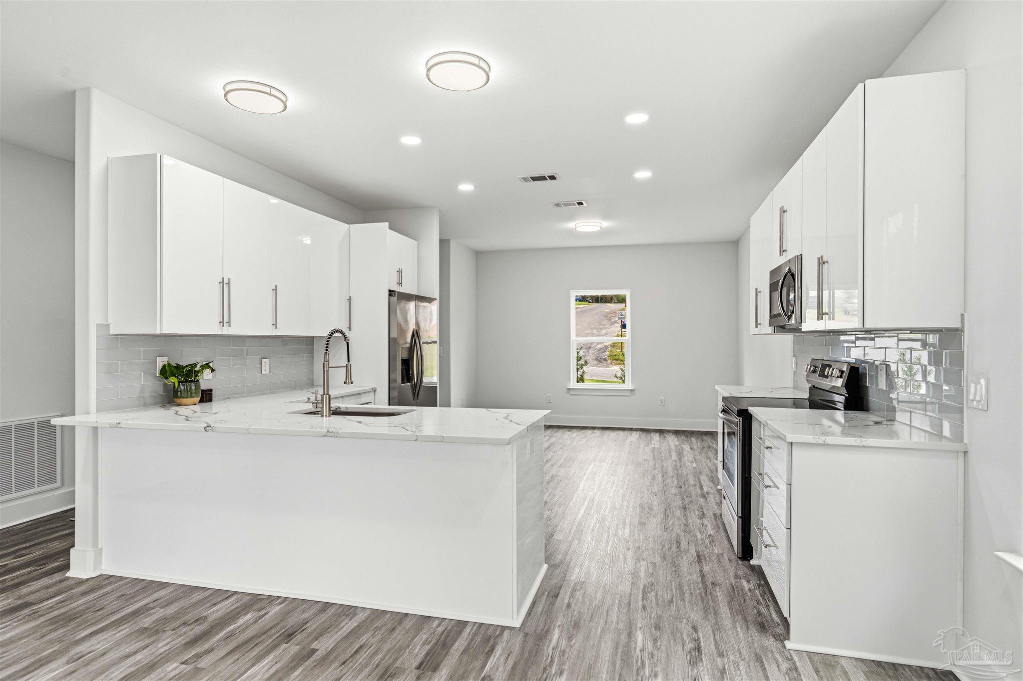 4446 Antioch Road Crestview, FL 32536 - Photo 9 of 43 a large kitchen with stainless steel appliances granite countertop a stove a sink dishwasher and a refrigerator with wooden floor