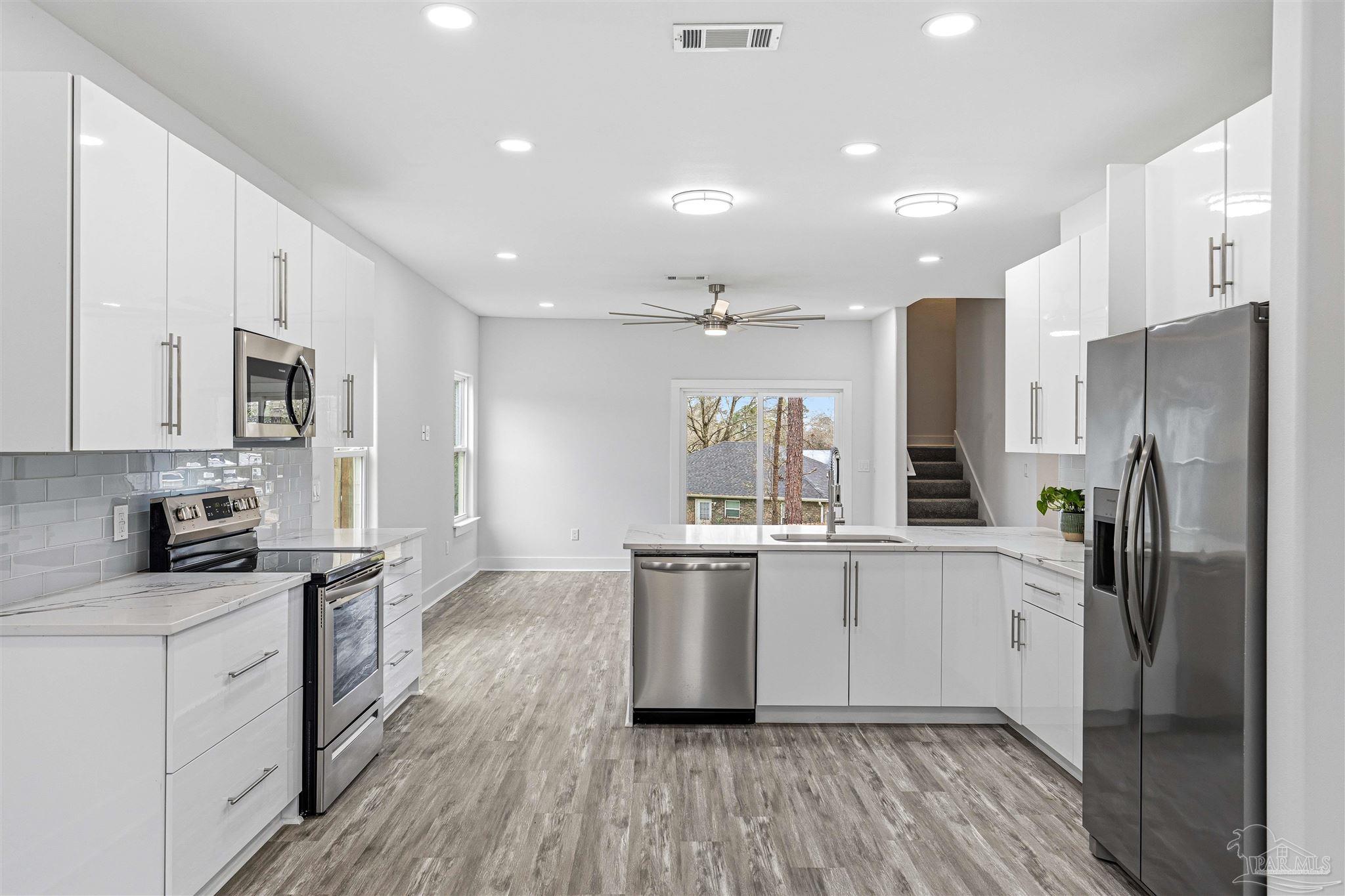 4446 Antioch Road Crestview, FL 32536 - Photo 10 of 43 a kitchen with stainless steel appliances a refrigerator a sink dishwasher a stove top oven a refrigerator and white cabinets with wooden floor