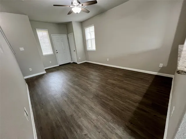 an empty room with wooden floor and windows
