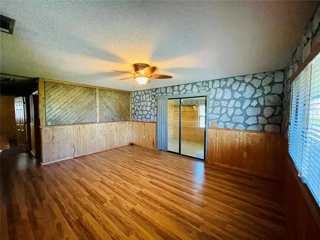 a view of a room with wooden floor fan and windows