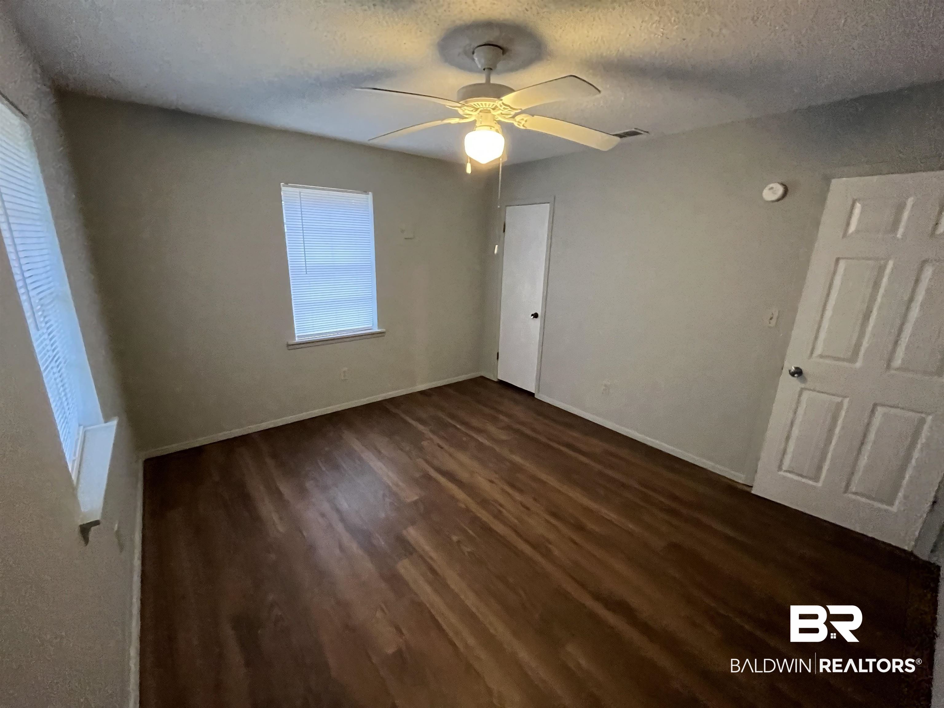 103 Roadway Street Brewton, AL 36426 - Photo 10 of 13 Unfurnished bedroom featuring a textured ceiling, dark hardwood / wood-style floors, and ceiling fan