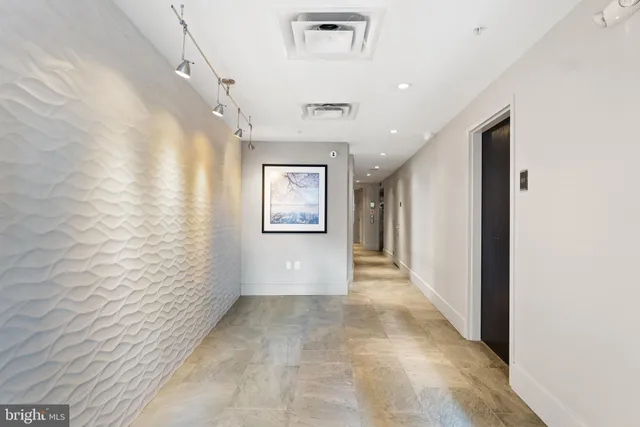a view of a hallway with wooden floor and a bathroom