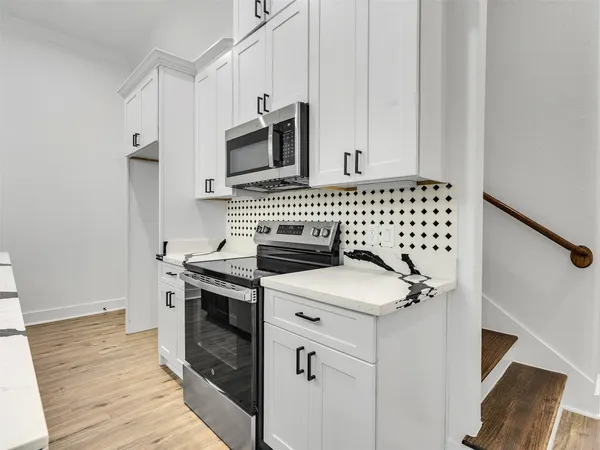 a kitchen with white cabinets and appliances