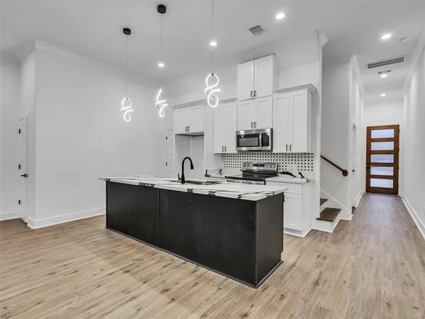 a kitchen with stainless steel appliances granite countertop a sink a stove and a wooden floors