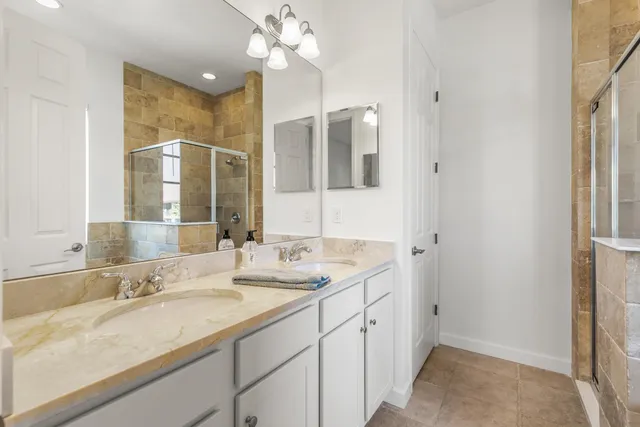 a bathroom with a granite countertop sink a large mirror and a shower