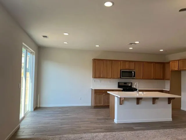 a kitchen with kitchen island a stove top oven a sink a counter space and cabinets