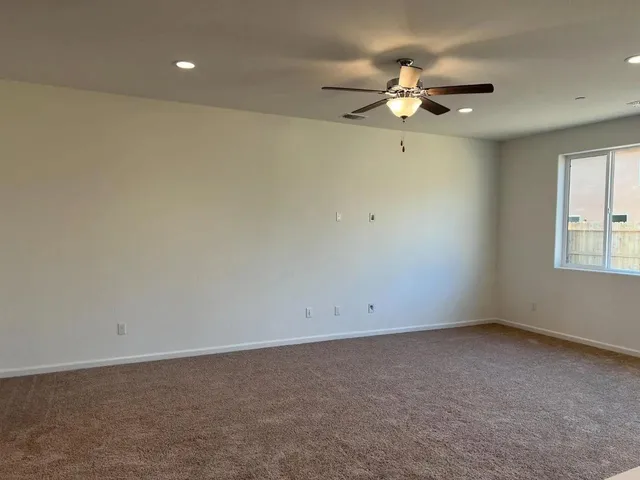 an empty room with a ceiling fan and window