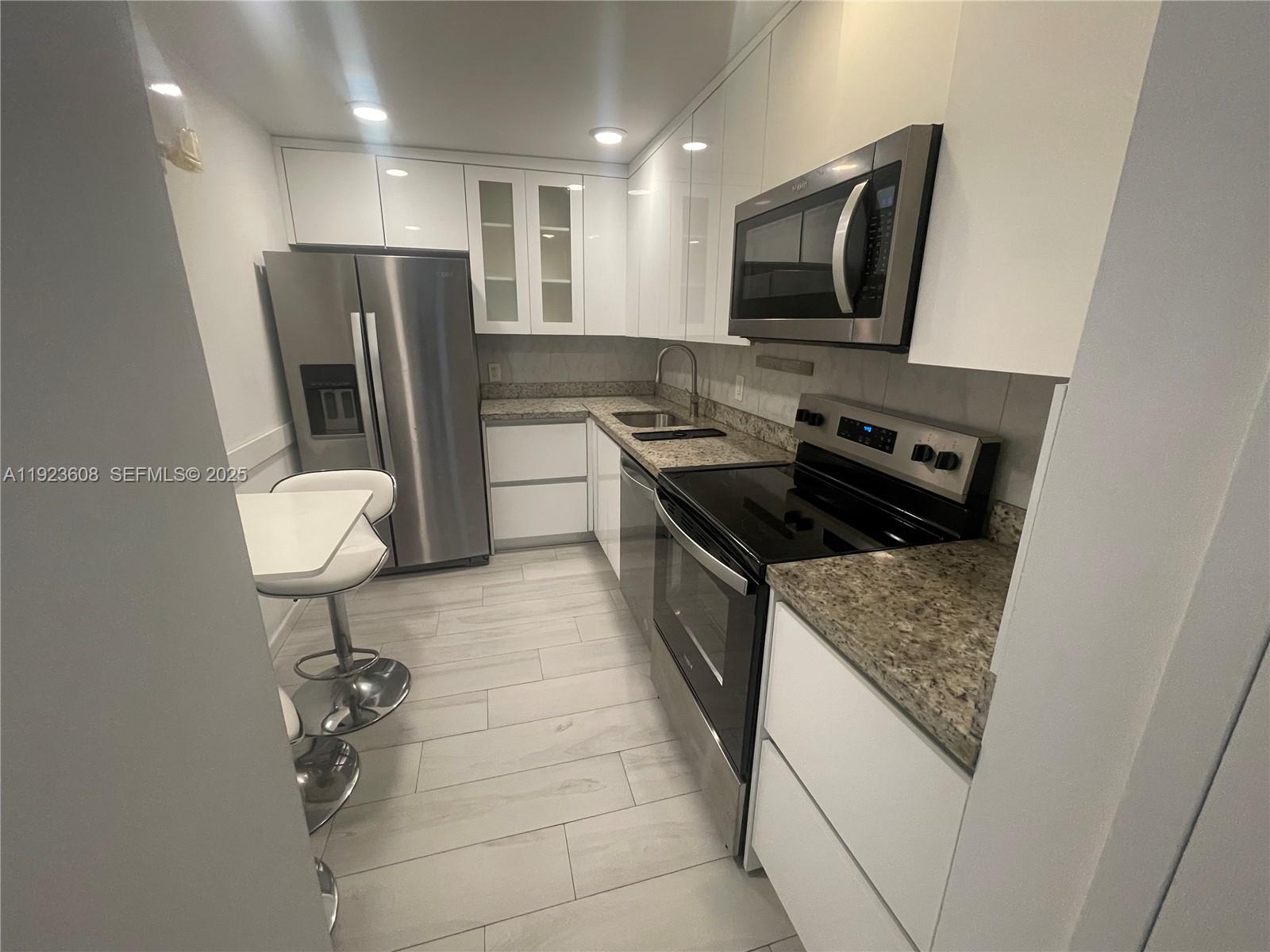6969 Collins Avenue, Unit 903 Miami Beach, FL 33141 - Photo 12 of 18 a kitchen with stainless steel appliances granite countertop a refrigerator and a stove top oven
