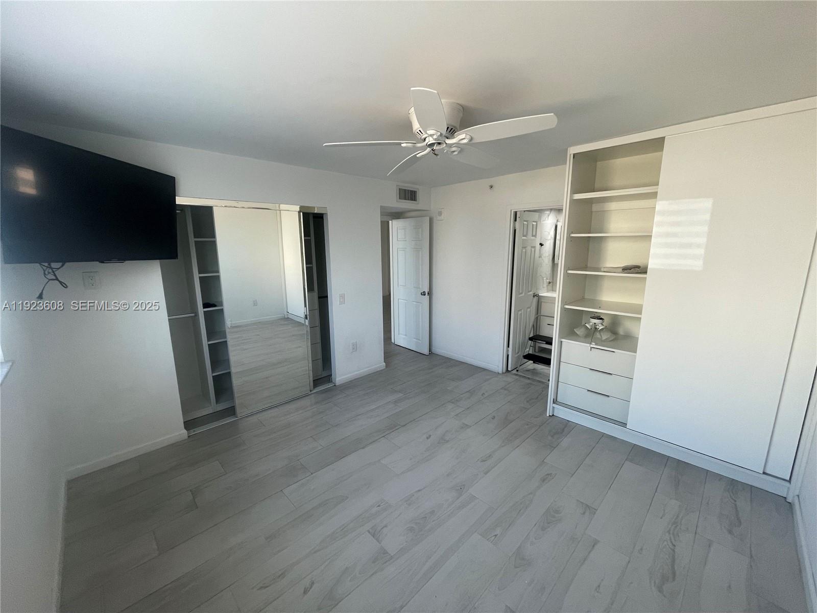 6969 Collins Avenue, Unit 903 Miami Beach, FL 33141 - Photo 9 of 18 an empty room with wooden floor cabinet and a flat screen tv