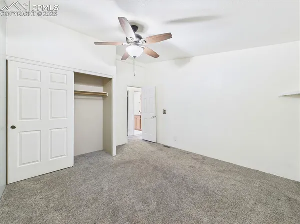 a view of an empty room with chandelier fan and a window