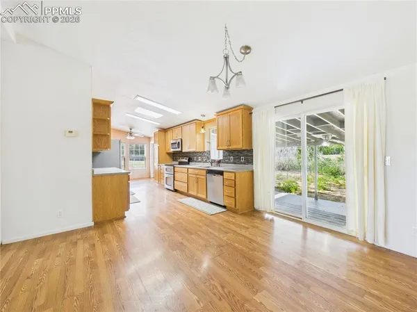 a view of a kitchen with kitchen island a counter top space wooden floor and stainless steel appliances