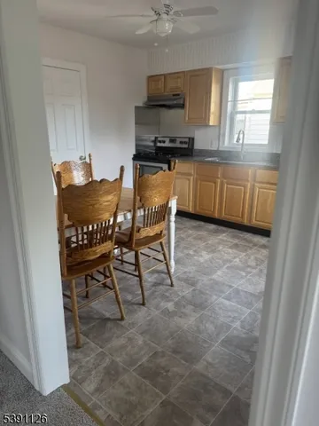 a kitchen with stainless steel appliances a sink a stove a microwave a dining table and chairs