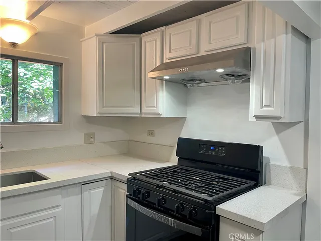 a kitchen with granite countertop a stove and a white cabinets
