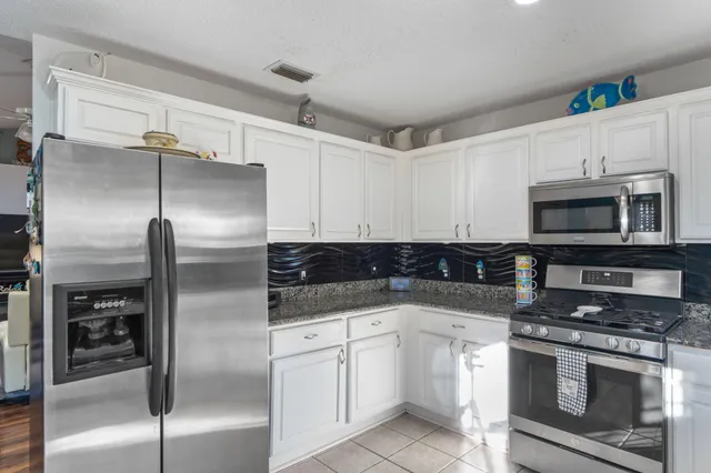 a kitchen with stainless steel appliances granite countertop a stove a sink and a microwave