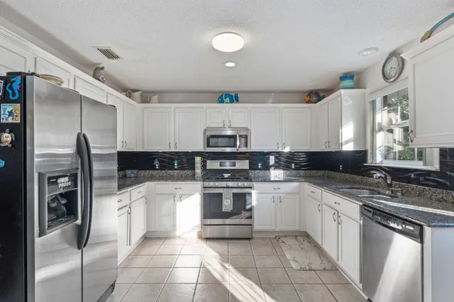 a kitchen with stainless steel appliances kitchen island granite countertop a refrigerator a stove a microwave oven a dining table and chairs with wooden floor