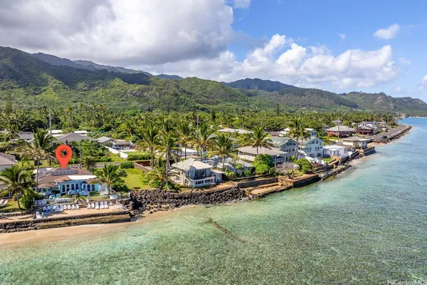 an aerial view of a houses with a yard and mountain view in back