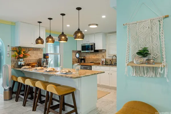 a kitchen with stainless steel appliances kitchen island granite countertop a table chairs and a refrigerator