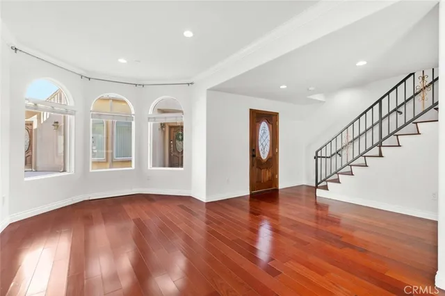 a view of an empty room with wooden floor and windows