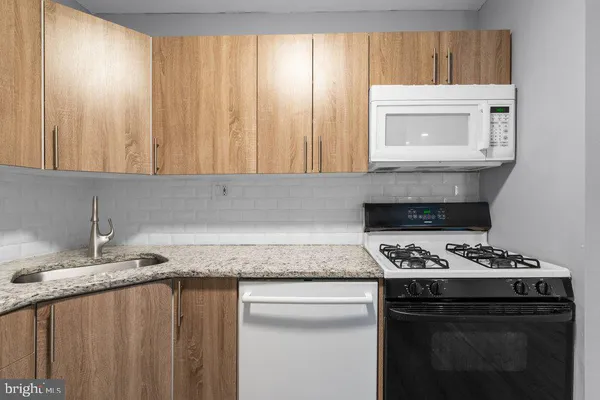 a kitchen with granite countertop a sink stove and cabinets