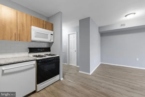 a kitchen with granite countertop wooden floor stainless steel appliances and a window