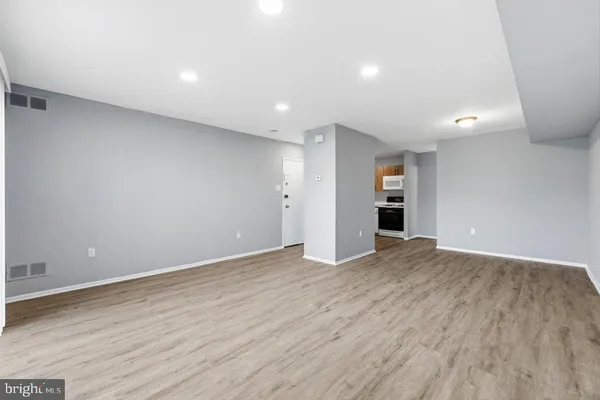 a view of an empty room with wooden floor and closet