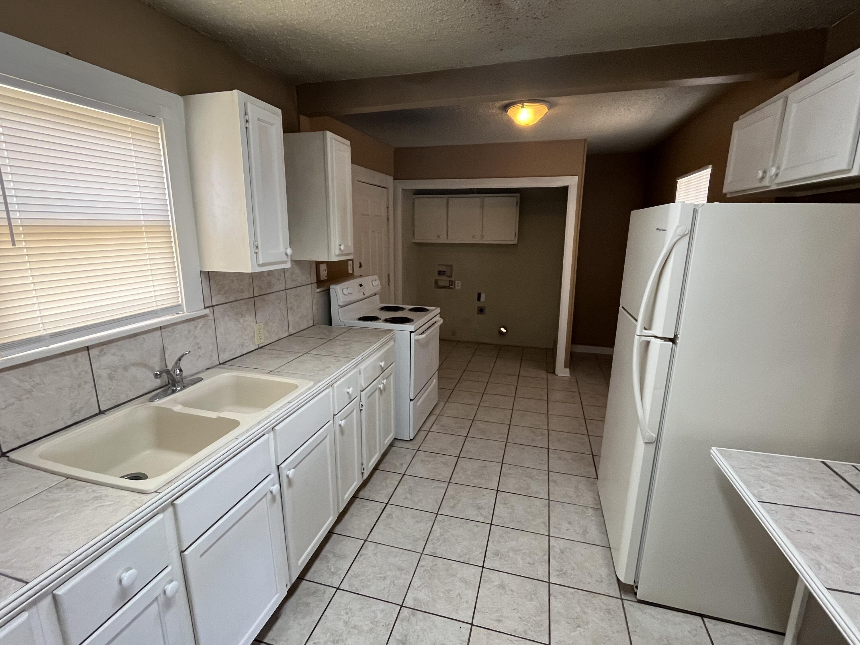 2111 25th Street Lubbock, TX 79411 - Photo 4 of 8 a kitchen with a sink a refrigerator and cabinets