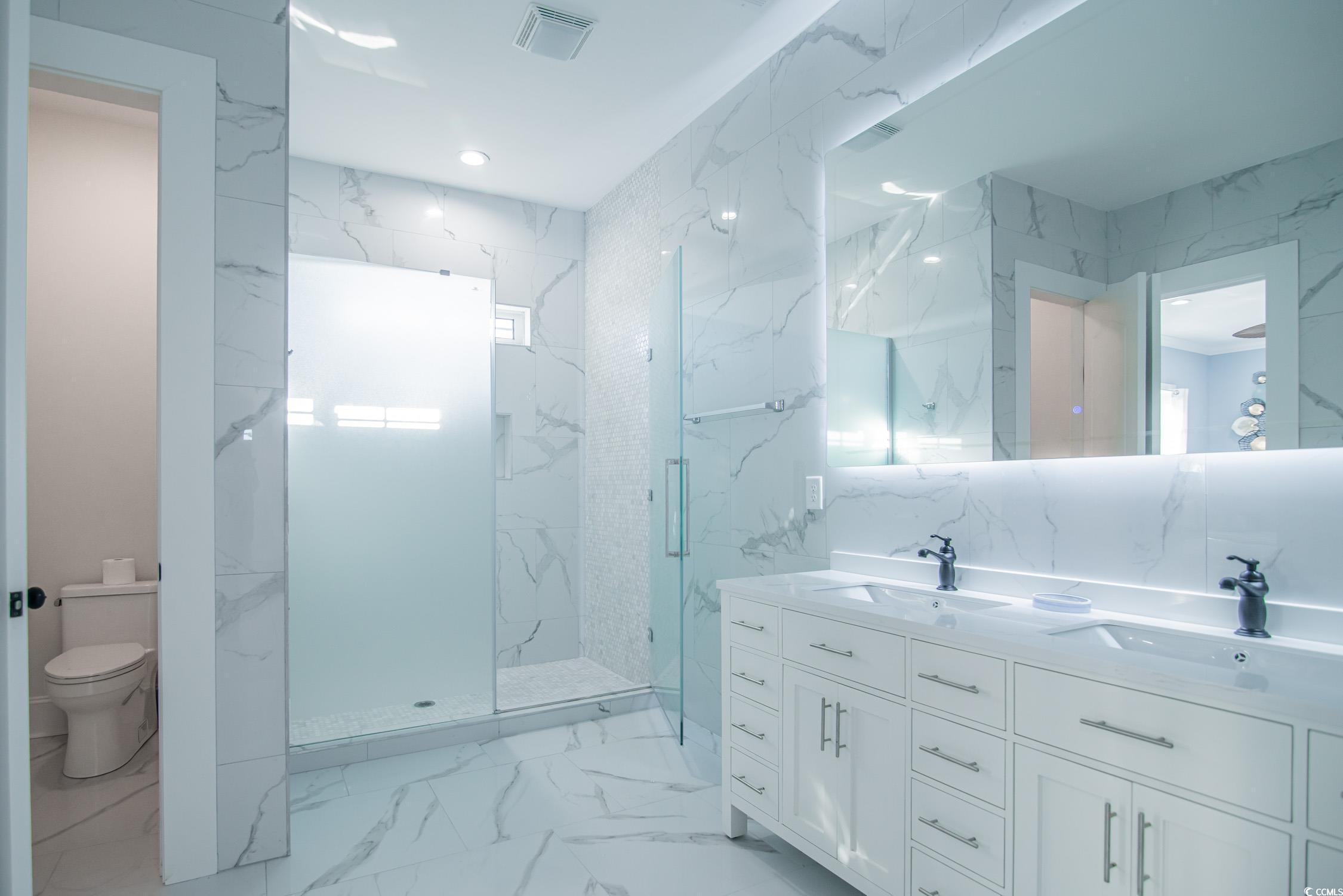139 Pioneer Loop Georgetown, SC 29440 - Photo 34 of 39 Full bath featuring light marble finish flooring, double vanity, tile walls, a marble finish shower, and stone wall