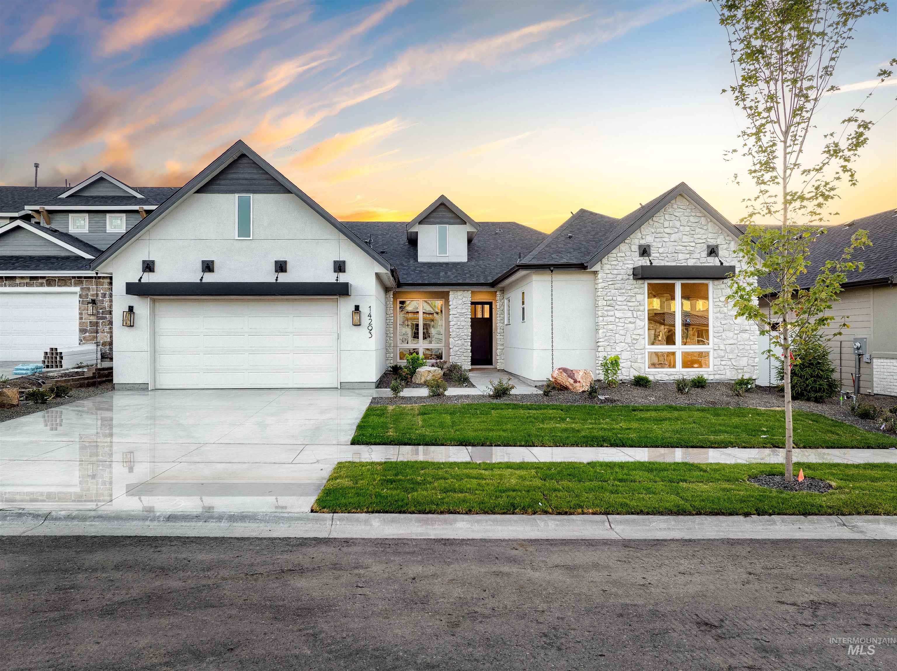 View of front facade with stone siding, concrete driveway, a yard, an attached garage, and stucco siding