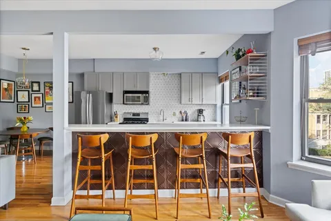 a blue kitchen with large windows and more cabinets
