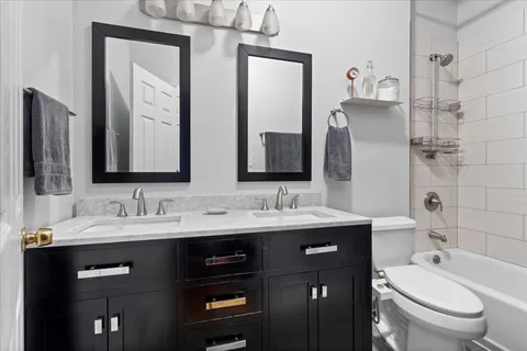 a bathroom with a double vanity sink toilet mirror and shower