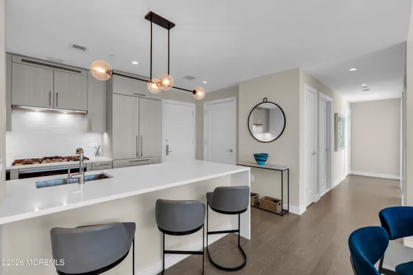 a large white kitchen with a stove a refrigerator a sink a couch and a chandelier