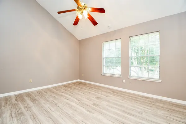 an empty room with wooden floor and windows