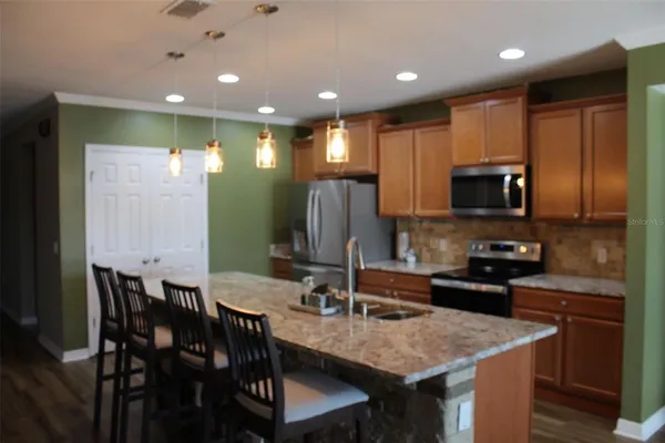 a kitchen with stainless steel appliances granite countertop a kitchen island hardwood floor sink and stove