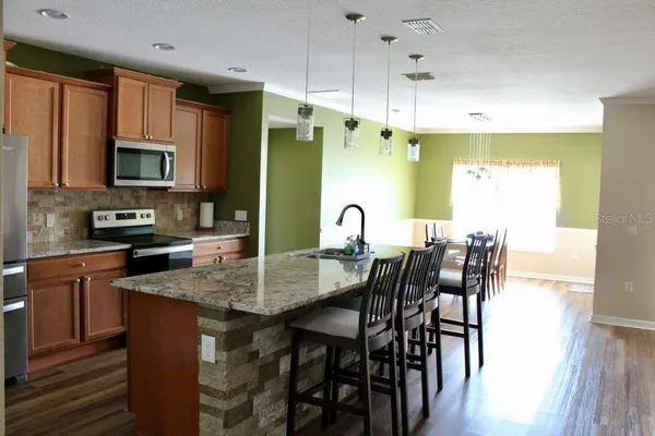 a kitchen with stainless steel appliances granite countertop a stove top oven a sink a dining table and chairs