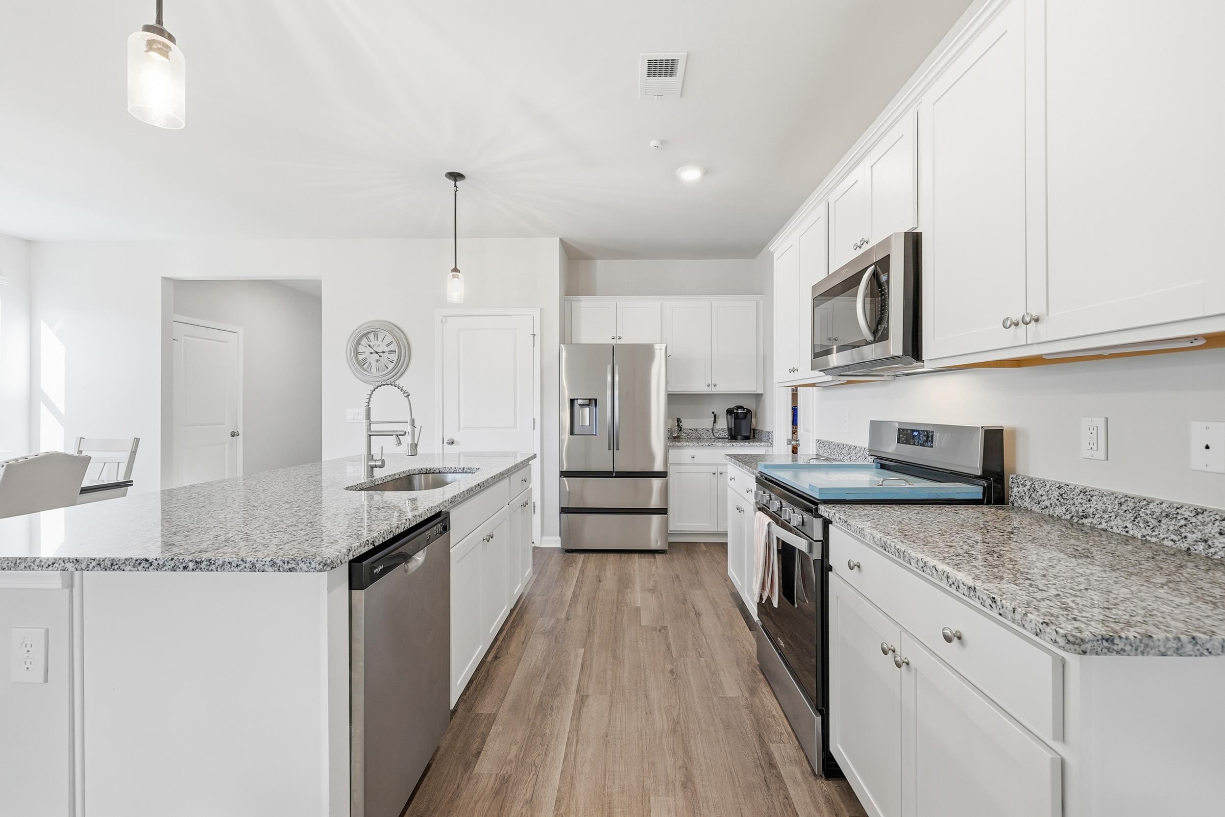 308 Picnic Basket Place Longs, SC 29568 - Photo 12 of 40 Kitchen with appliances with stainless steel finishes, pendant lighting, white cabinetry, a kitchen island with sink, and light stone counters