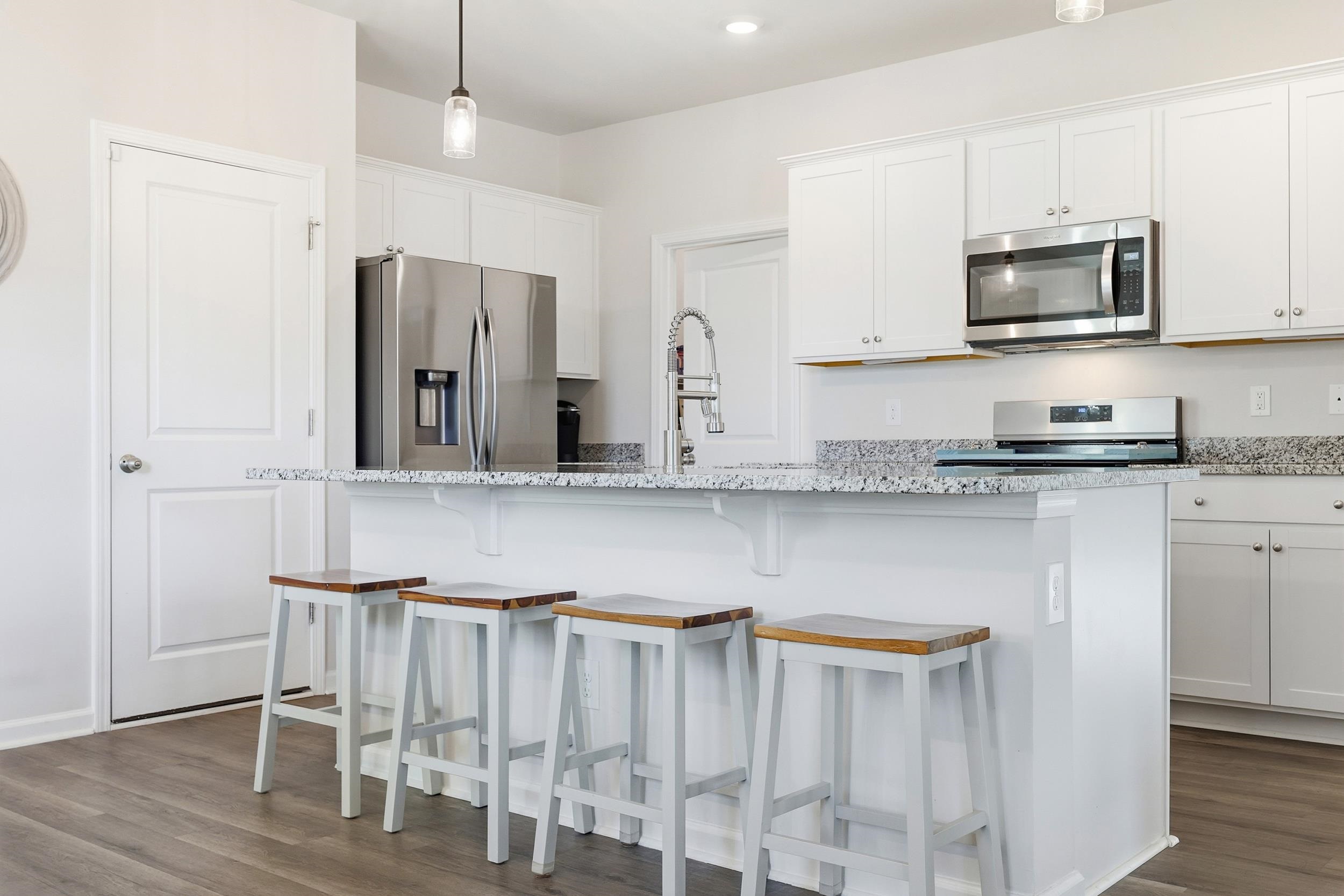 308 Picnic Basket Place Longs, SC 29568 - Photo 10 of 40 Kitchen with stainless steel appliances, white cabinetry, an island with sink, dark wood-style flooring, and light stone counters
