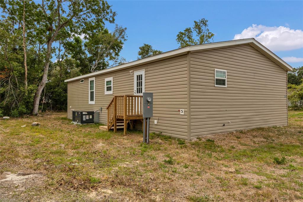 3264 Stephens Boulevard Spring Hill, FL 34606 - Photo 27 of 35 a view of a house with a yard and lawn chairs under an umbrella