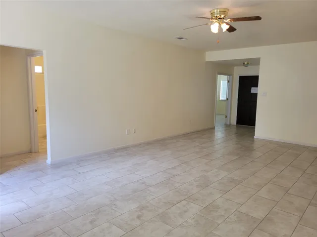 a view of an empty room with a chandelier fan