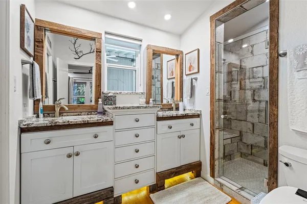 a bathroom with a granite countertop sink a mirror and a shower
