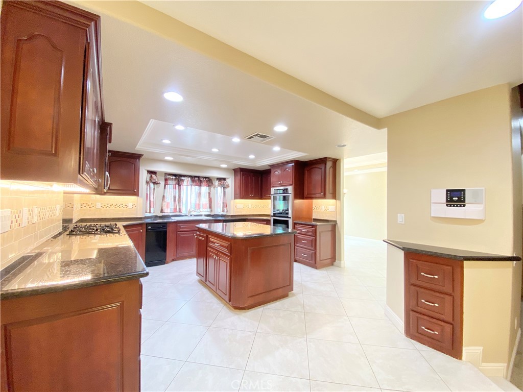 14670 Gilman Springs Road Moreno Valley, CA 92555 - Photo 11 of 50 a kitchen with stainless steel appliances kitchen island granite countertop a refrigerator and a stove top oven