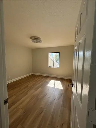 a view of an empty room with wooden floor and a window