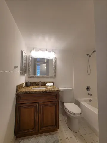a bathroom with a granite countertop toilet a sink a mirror and bathtub