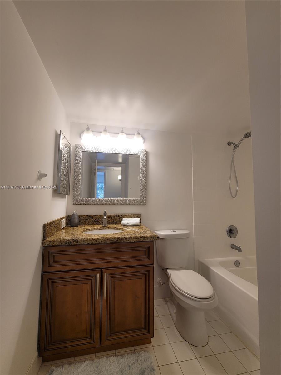 2133 Renaissance Boulevard, Unit 306 Miramar, FL 33025 - Photo 36 of 41 a bathroom with a granite countertop toilet a sink a mirror and bathtub