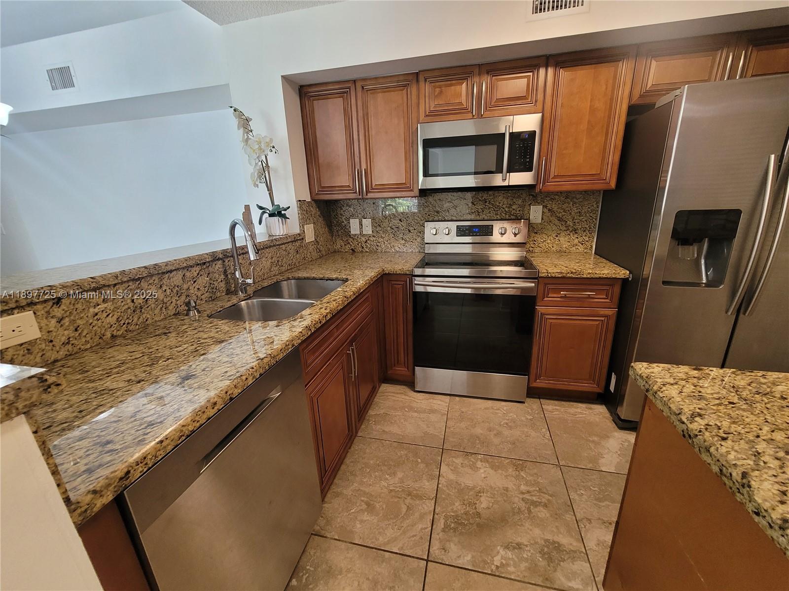 2133 Renaissance Boulevard, Unit 306 Miramar, FL 33025 - Photo 5 of 41 a kitchen with stainless steel appliances granite countertop a sink stove and microwave