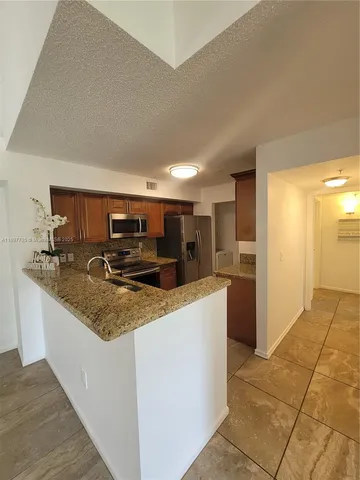 a large kitchen with kitchen island a sink a counter top and stainless steel appliances