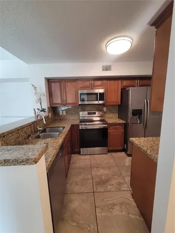 a large kitchen with granite countertop a stove top oven a sink dishwasher and a refrigerator