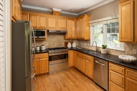 a kitchen with stainless steel appliances a sink cabinets and a window
